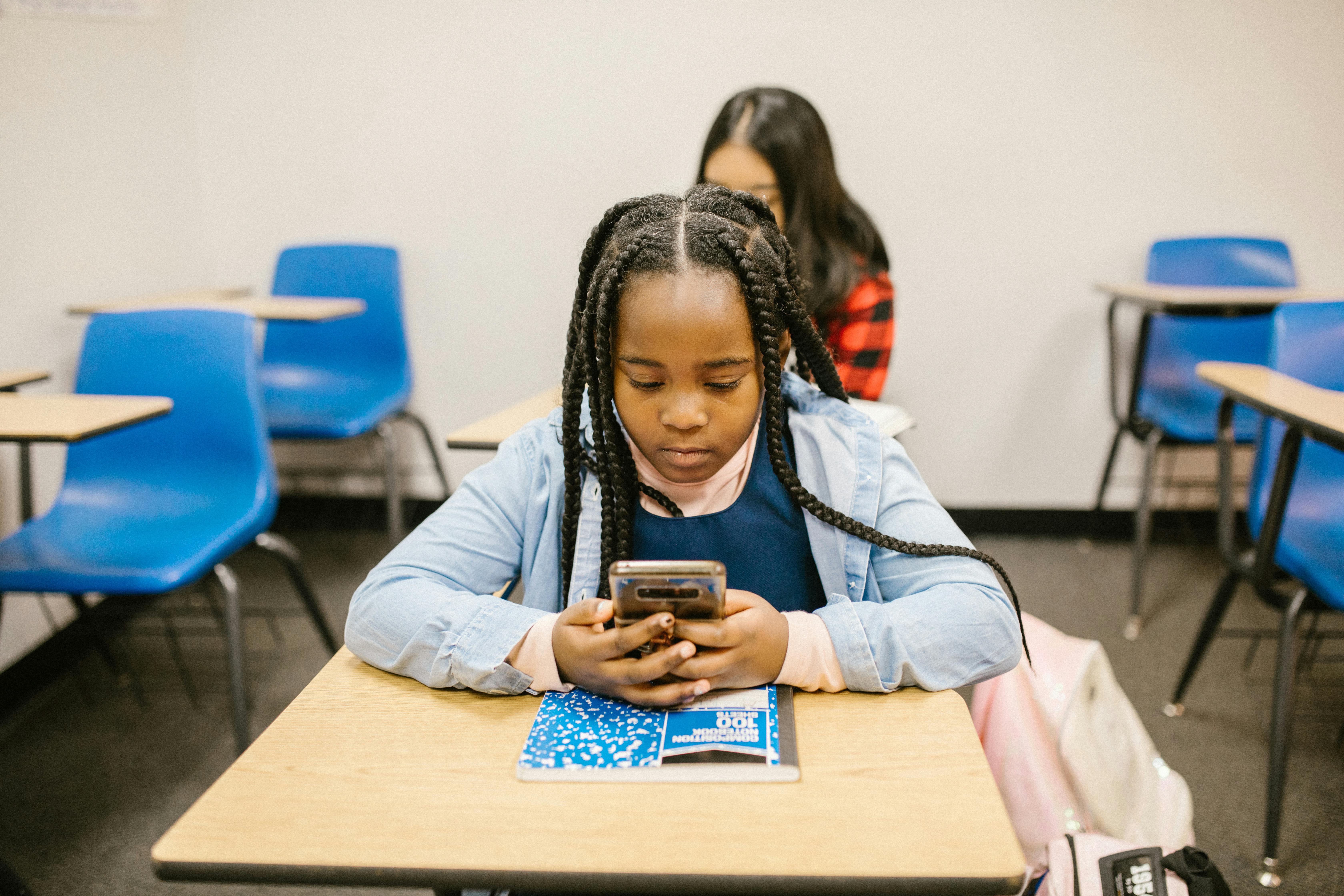 Student using a mobile phone at her desk highlighting online safety in schools
